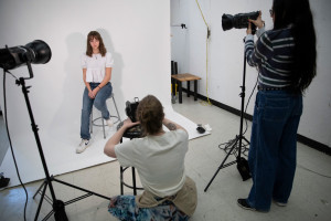 Students doing a photoshoot in front of a white backdrop in the photo studios.