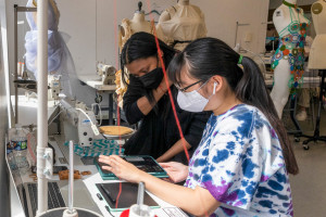 Student and professor discussing fashion design work.