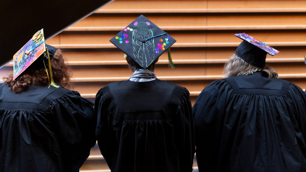 Three Moore graduates sitting together at the 2023 Commencement ceremony at the Kimmel Cultural Campus.