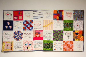 A 24-panel quilt designed by Rachel Wallis MA '16 called Inheritance features panels in white, red, green and purple fabrics that include embroidered words.