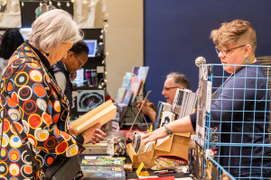 An attendee visits Christine Larsen's exhibition table at the Comics Expo.