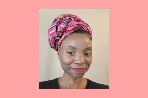 A black woman is wearing a black shirt and is wearing a red, purple and orange head wrap.