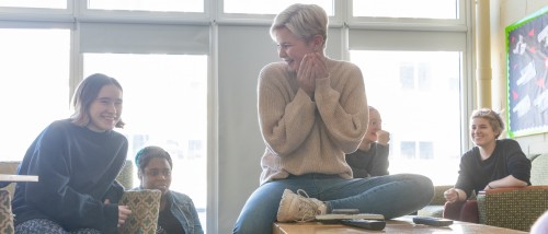 Students talking and laughing in a Moore residence hall lounge.