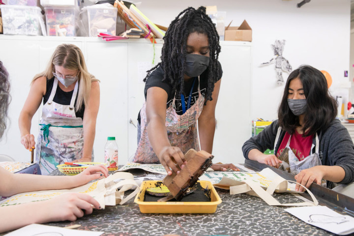 Three SADI 2021 students working on their art at the Fabric Workshop and Museum. The student in the middle is reaching out to add ink on their stamp.