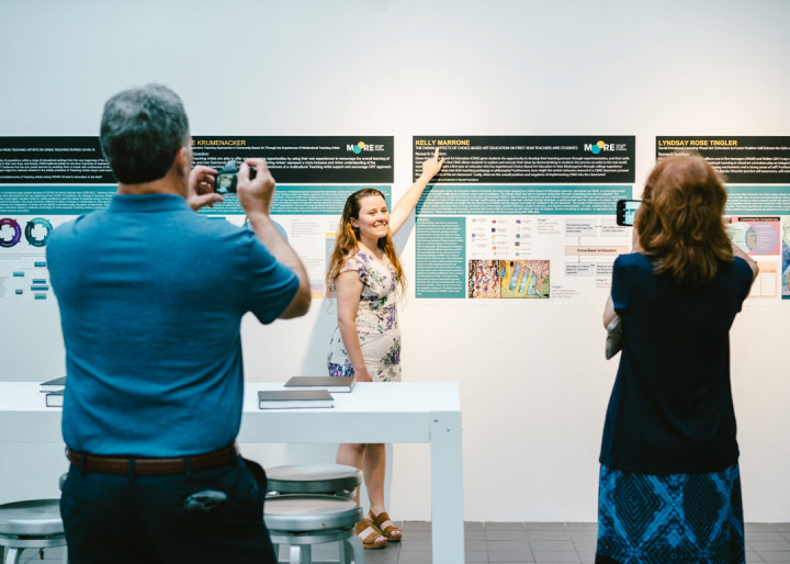 Photo of Kelly Marrone pointing at her thesis presentation at the Art Education 2021 Commencement