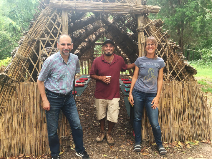 Three people posing for a photo in front of a wooden structure