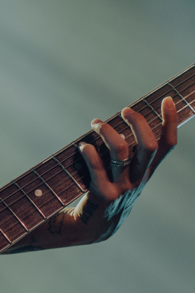 A closeup photograph of a musicians hand along the fretboard of a guitar.