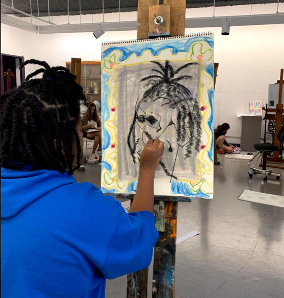 Over the shoulder photo of a student drawing a self-portrait